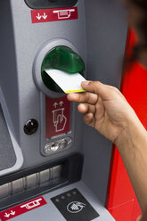 Hand einer Frau, die eine Kreditkarte in einen Geldautomaten steckt, Nahaufnahme - ABZF02164