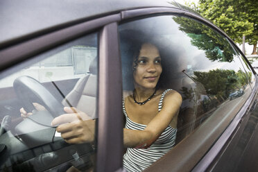 Frau, die ein Auto fährt und aus dem Autofenster schaut - ABZF02168