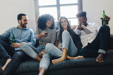 Glückliche Freunde sitzen auf dem Sofa und sehen fern - GIOF02785