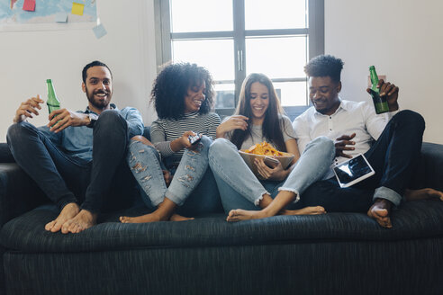 Glückliche Freunde sitzen auf dem Sofa - GIOF02786