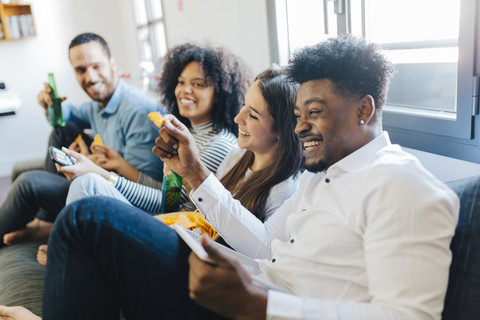 Glückliche Freunde sitzen auf dem Sofa, lizenzfreies Stockfoto