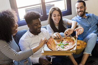 Glückliche Freunde sitzen auf dem Sofa und teilen sich eine Pizza - GIOF02795