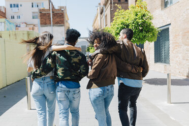 Rear view of stylish friends walking on urban street - GIOF02817