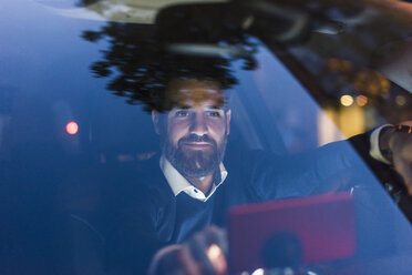 Businessman using navigation device in car at night - UUF10881