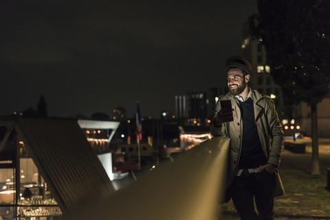 Stilvoller junger Mann mit Mobiltelefon in der Stadt bei Nacht, lizenzfreies Stockfoto