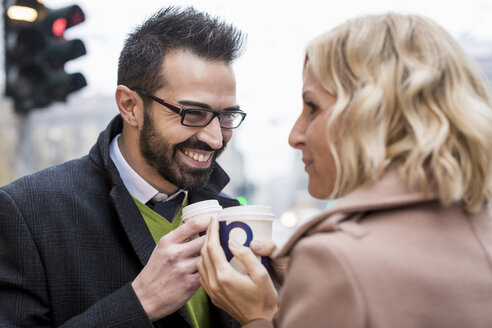 Lächelnder Geschäftsmann und Geschäftsfrau mit Kaffee zum Mitnehmen in der Stadt - MAUF01100