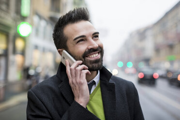 Smiling businessman in the city on cell phone - MAUF01106