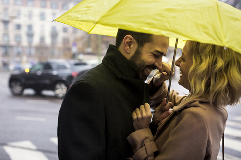 Glückliches Geschäftspaar unter einem Regenschirm in der Stadt - MAUF01109