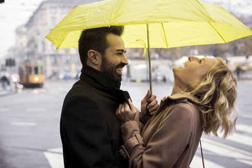 Glückliches Geschäftspaar unter einem Regenschirm in der Stadt - MAUF01110