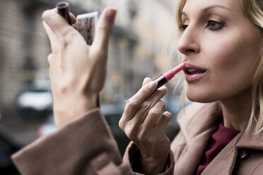 Geschäftsfrau trägt Lippenstift im Freien auf - MAUF01111