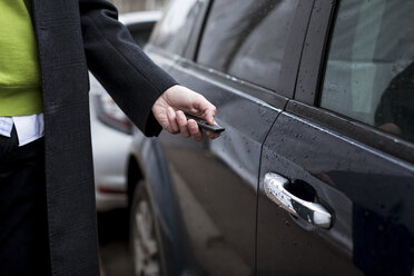 Nahaufnahme eines Geschäftsmannes, der ein Auto mit einer Fernbedienung öffnet - MAUF01114