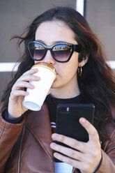 Portrait of young woman with coffee to go taking selfie with smartphone - RTBF00949