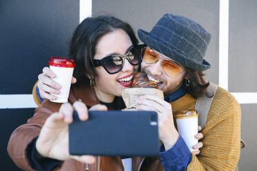 Young couple with croissant and coffee to go taking selfie with smartphone - RTBF00952