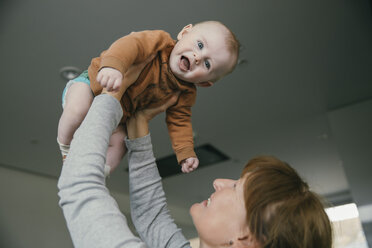 Grandmother lifting up baby at home - MFF03679