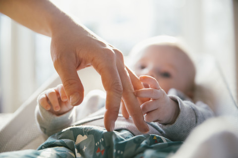 Baby berührt die Hand der Frau, lizenzfreies Stockfoto