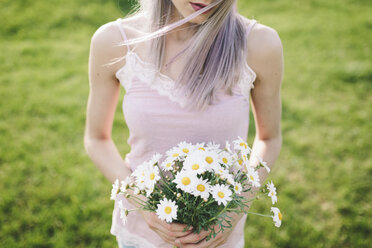 Frau hält einen Strauß Gänseblümchen, Teilansicht - GIOF02824