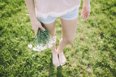 Woman holding bunch of daisies, partial view - GIOF02827