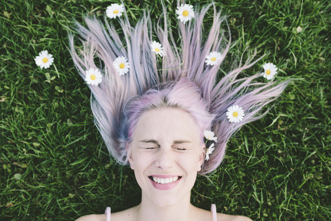 Portrait of woman lying on grass with eyes closed and daisies on hair stock photo