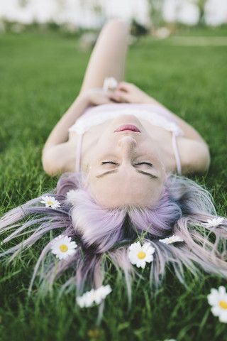 Frau im Gras liegend mit Blumen im Haar, lizenzfreies Stockfoto