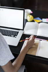 Close-up of woman at home using laptop taking notes - GIOF02851