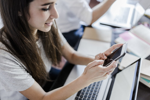 Busy couple at home using laptop and smartphone stock photo