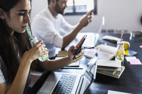 Busy couple at home using laptop and smartphone stock photo