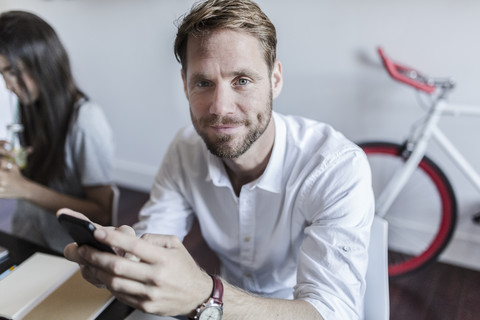 Portrait of smiling man at home using smartphone stock photo