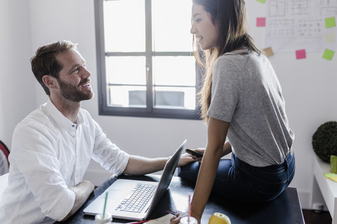 Affectionate couple with laptop at home talking stock photo