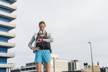 Woman having a break from exercising looking at smartwatch - UUF10937