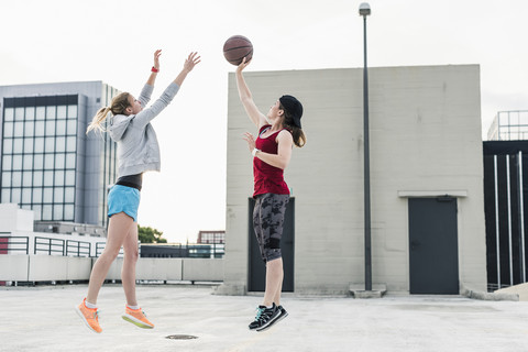 Zwei Frauen spielen Basketball auf einem Parkdeck in der Stadt, lizenzfreies Stockfoto