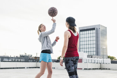 Frau beim Basketballspielen auf einem Parkdeck in der Stadt - UUF10944