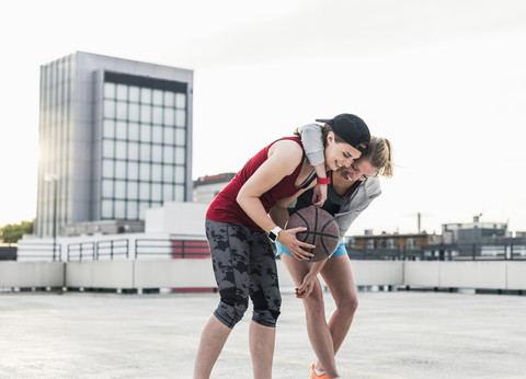 Zwei glückliche Frauen beim Basketball auf einem Parkdeck in der Stadt, lizenzfreies Stockfoto