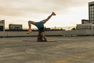 Woman doing a headstand on parking level in the city - UUF10962