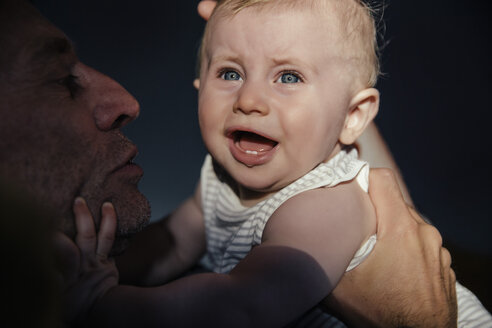 Portrait crying baby boy on his father's arms - MFF03691