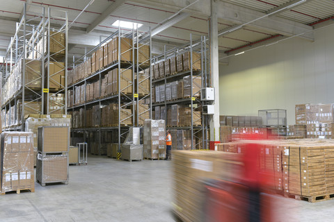 Man in factory hall and moving forklift stock photo