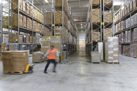 Man in factory hall using pallet jack stock photo