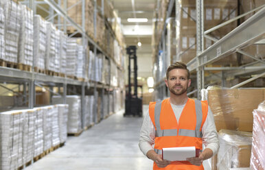 Portrait of confident man in factory hall wearing safety vest holding clipboard - LYF00754