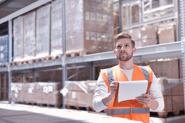 Man in factory hall wearing safety vest holding clipboard - LYF00755