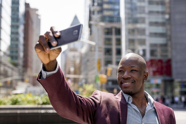 USA, New York City, Manhattan, stilvoller Geschäftsmann macht Selfie mit Smartphone - MAUF01144