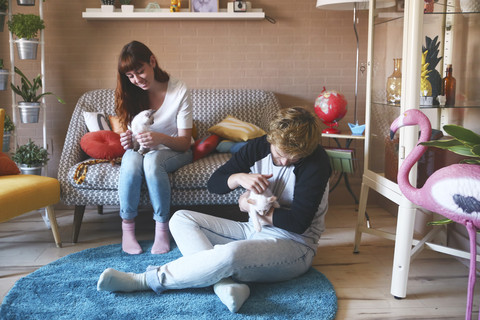 Junges Paar mit Kätzchen im Wohnzimmer, lizenzfreies Stockfoto