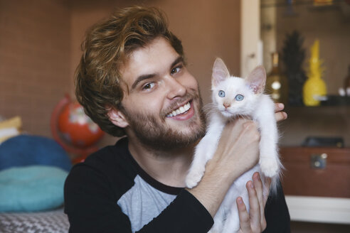 Portrait of smiling young man holding white kitten - RTBF00981