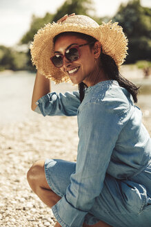 Portrait of happy woman wearing straw hat and sun glasses on the beach - SUF00160