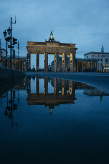 Deutschland, Berlin, Blick auf das Brandenburger Tor, das sich bei Nacht in einer Pfütze spiegelt - ZMF00484