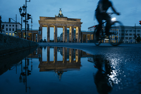 Deutschland, Berlin, Blick auf das Brandenburger Tor, das sich bei Nacht in einer Pfütze spiegelt, lizenzfreies Stockfoto