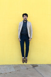 Young man jumping in the air in front of yellow wall - GIOF02875