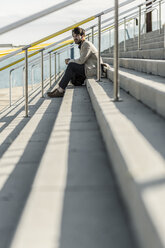 Nachdenklicher Mann sitzt auf einer Treppe im Freien - GIOF02884