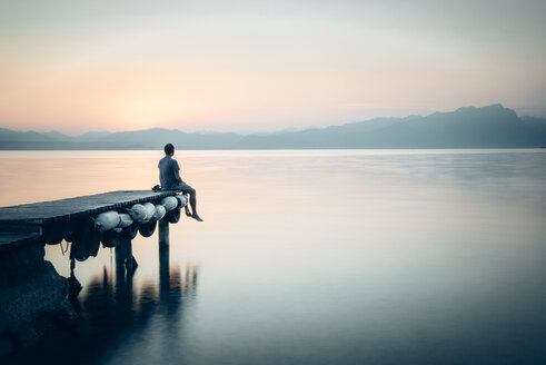 Italy, Lazise, man sitting on jetty looking at Lake Garda - IPF00393