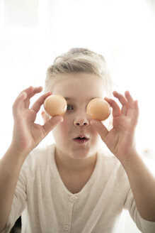 Porträt eines kleinen Mädchens mit zwei braunen Eiern - MOEF00028