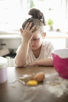 Kleines Mädchen beobachtet zerbrochenes Ei auf dem Küchentisch - MOEF00038