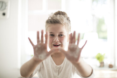 Portrait of smiling girl in the kitchen with dough on hands and face - MOEF00045
